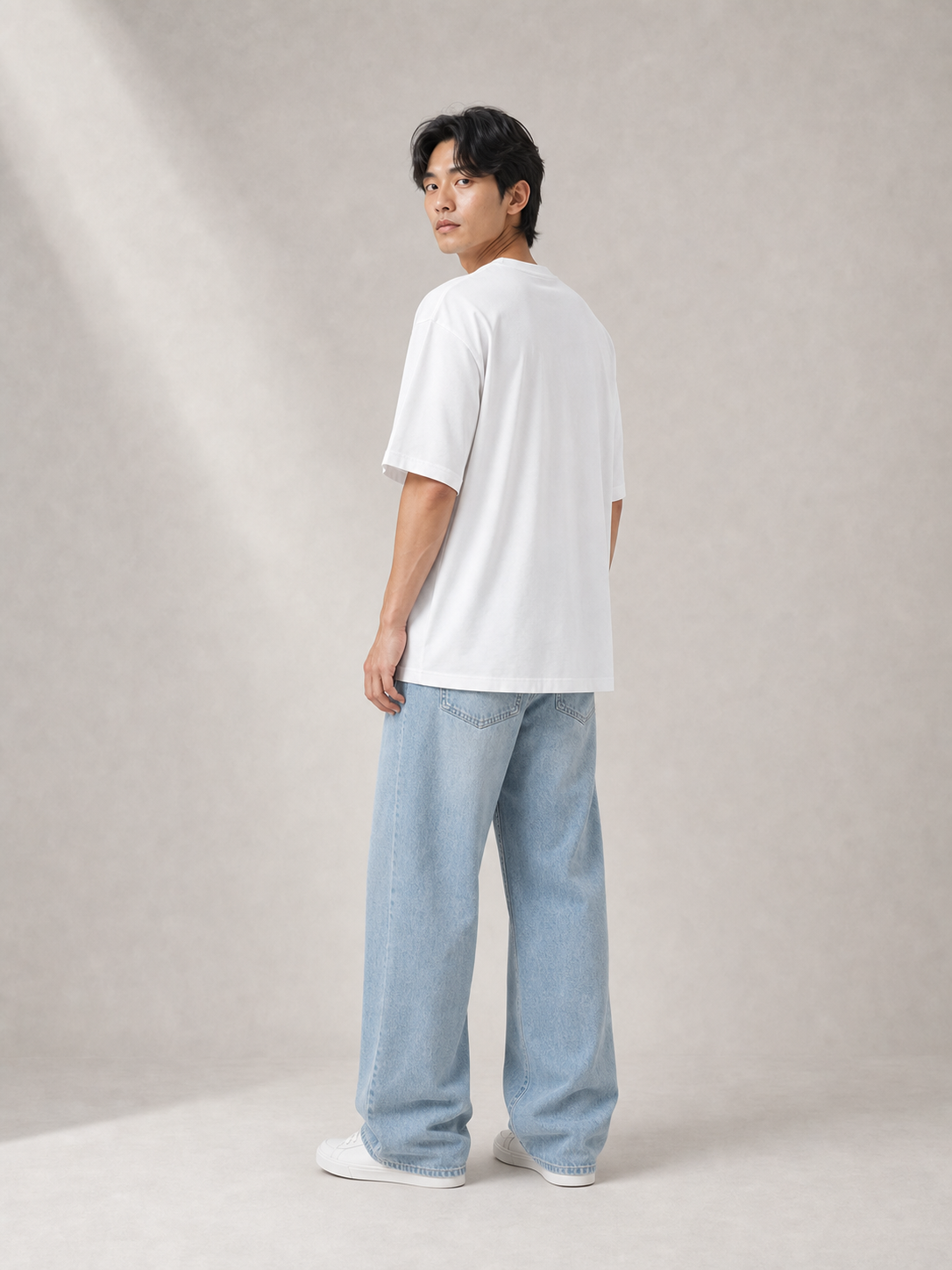 UOMO Relaxed White Tee rear three-quarter view on a male model in pale blue wide-leg jeans and white sneakers