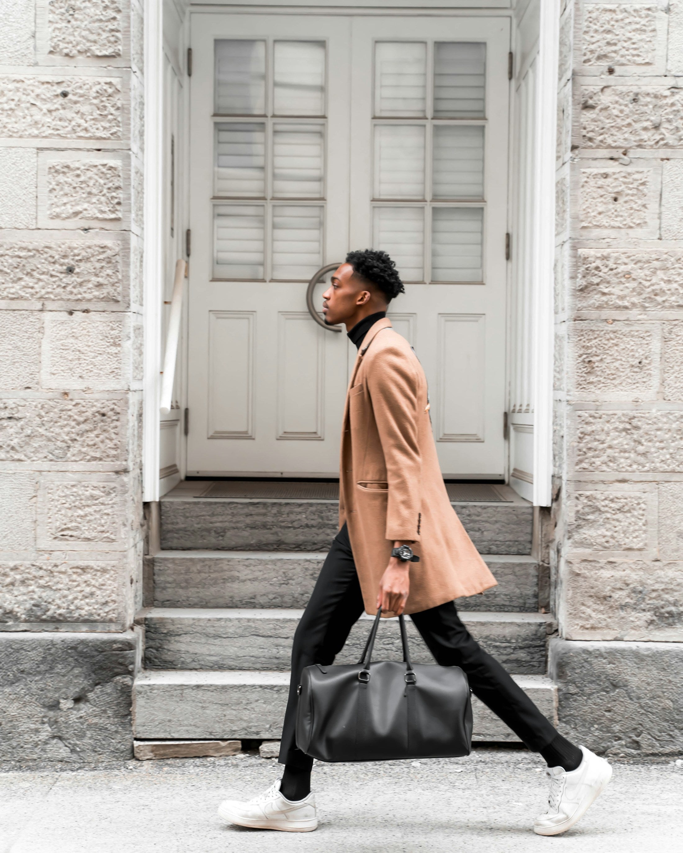 Man in a camel overcoat walking through the city