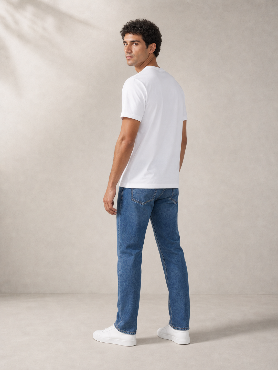 UOMO Essential White Tee rear three-quarter view on a male model in blue jeans and white sneakers