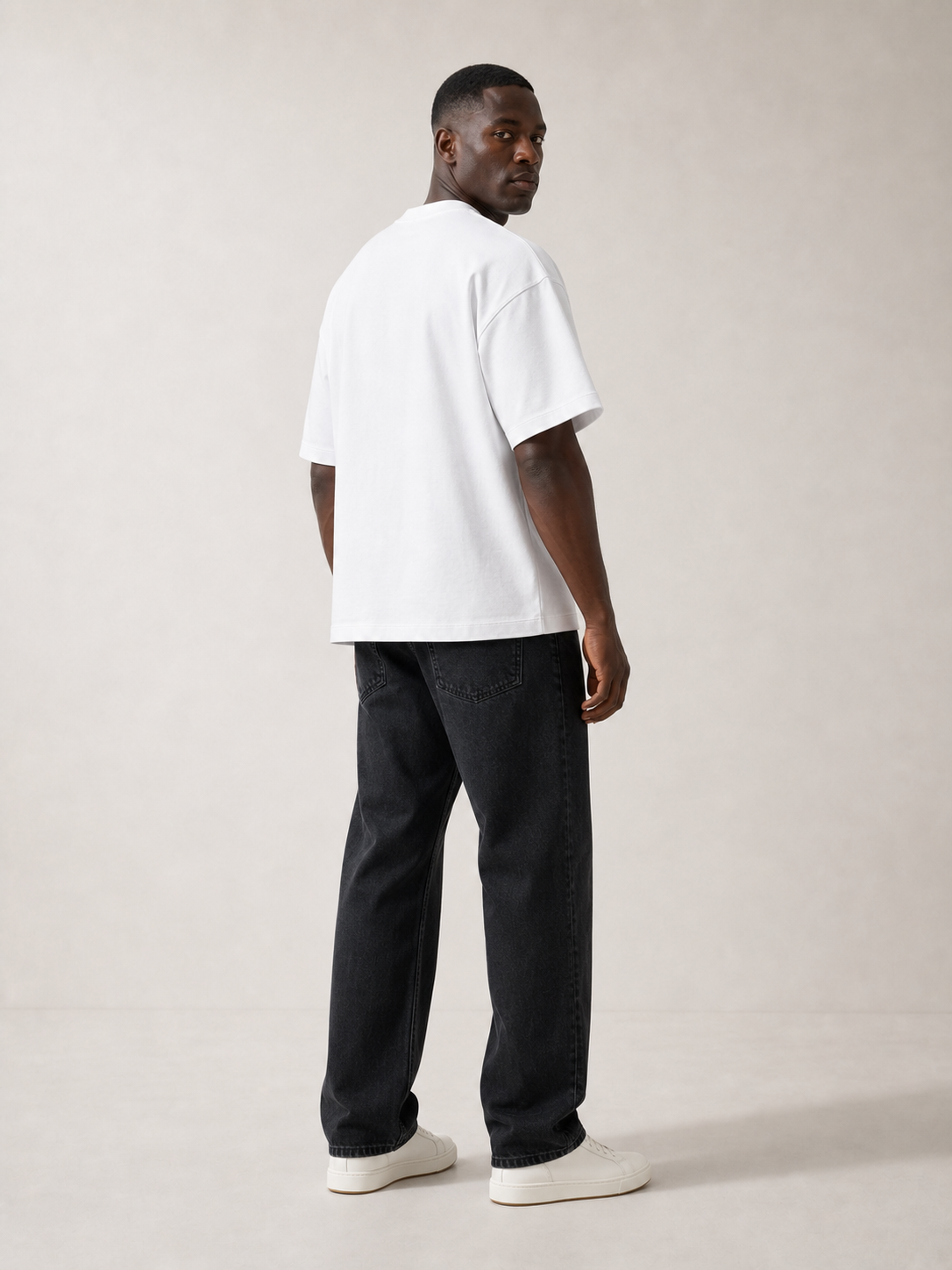 UOMO Heavyweight White Tee rear three-quarter view on a male model in washed black jeans and off-white sneakers