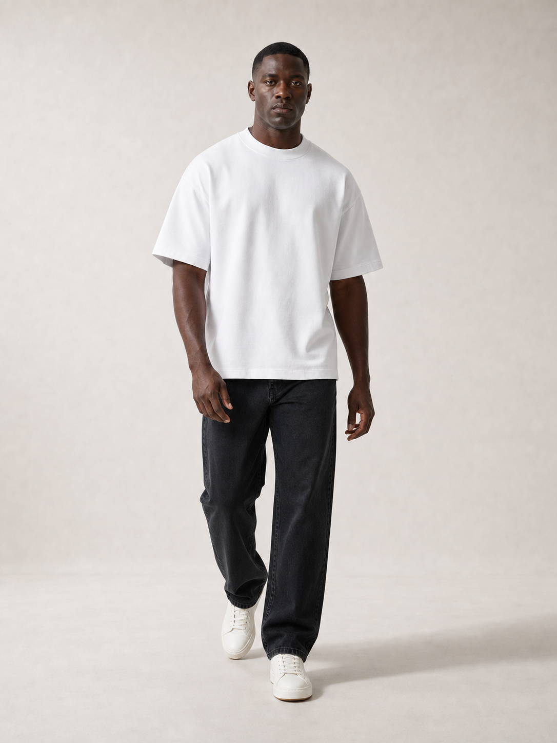 UOMO Heavyweight White Tee on a walking male model in washed black jeans and off-white sneakers