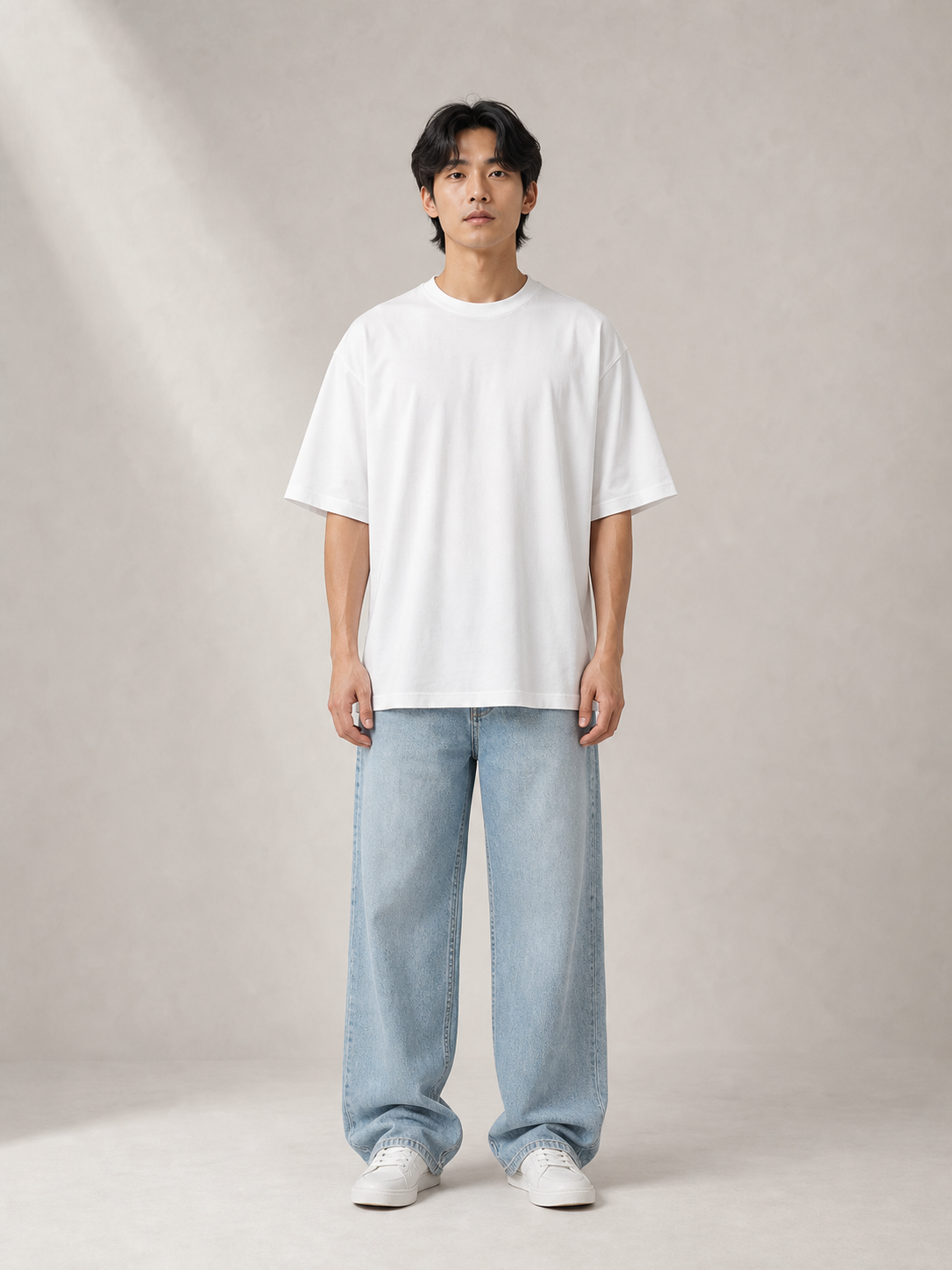 UOMO Relaxed White Tee front view on a male model in pale blue wide-leg jeans and white sneakers