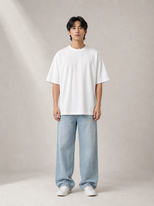 UOMO Relaxed White Tee front view on a male model in pale blue wide-leg jeans and white sneakers
