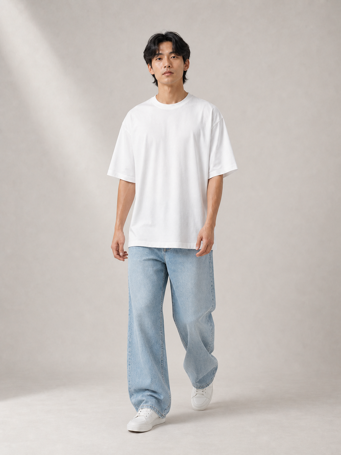 UOMO Relaxed White Tee on a walking male model in pale blue wide-leg jeans and white sneakers